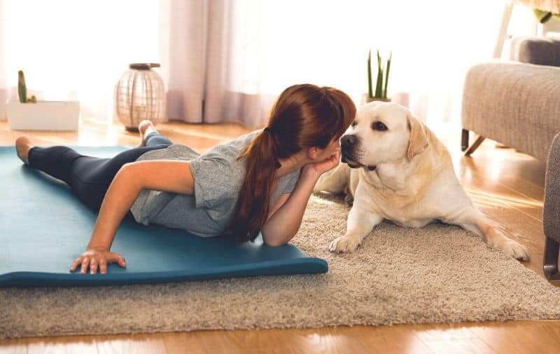 Ways to motivate yourself to work out today - girl on exercise mat next to dog