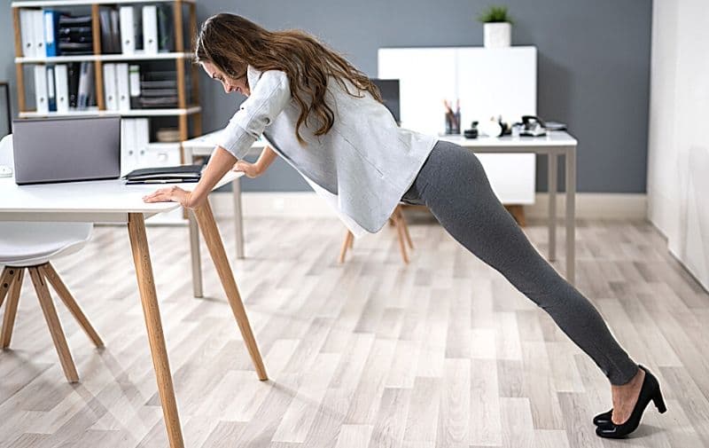 How to Stay Active When Working from Home - Woman doing incline pushups using her desk.