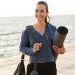 difference between yoga mat and exercise mat feature image - woman holding a yoga mat on a beach