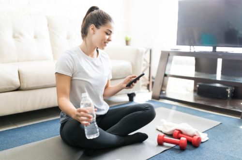 do home workout apps work - young woman sitting on the floor checking her mobile fitness app