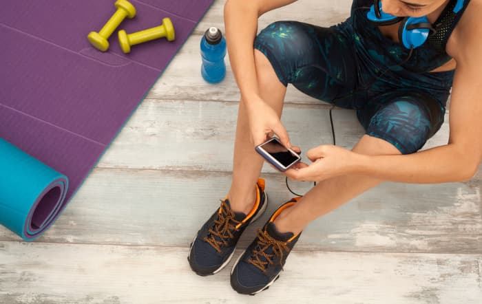 best home workout apps woman on the floor with her workout app next to yoga mat