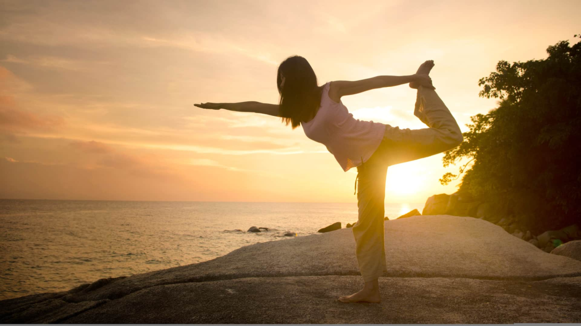 feature image for the best time to do yoga for weight loss - woman in nature doing dancer pose by the water during sunset
